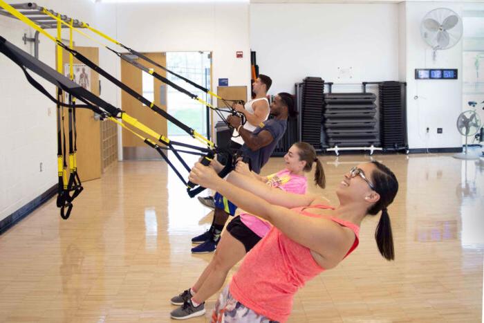 Students exercising using TRX bands during a group fitness class in the Activity Room.